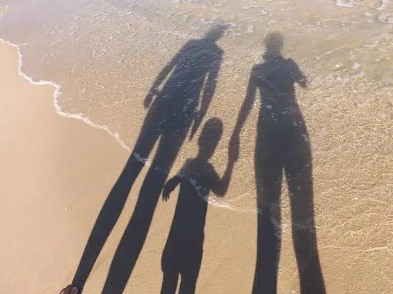 Schatten einer Familie mit Kind am Strand